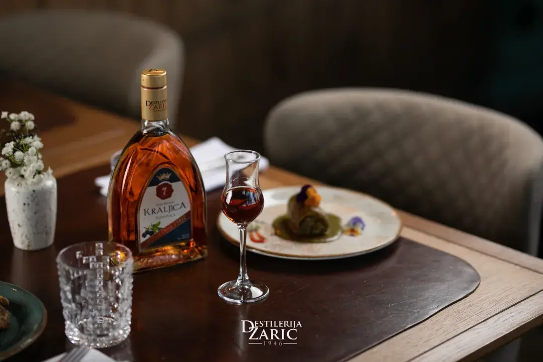 Flaša i čaša rakije Zarić na postavljenom restoranskom stolu